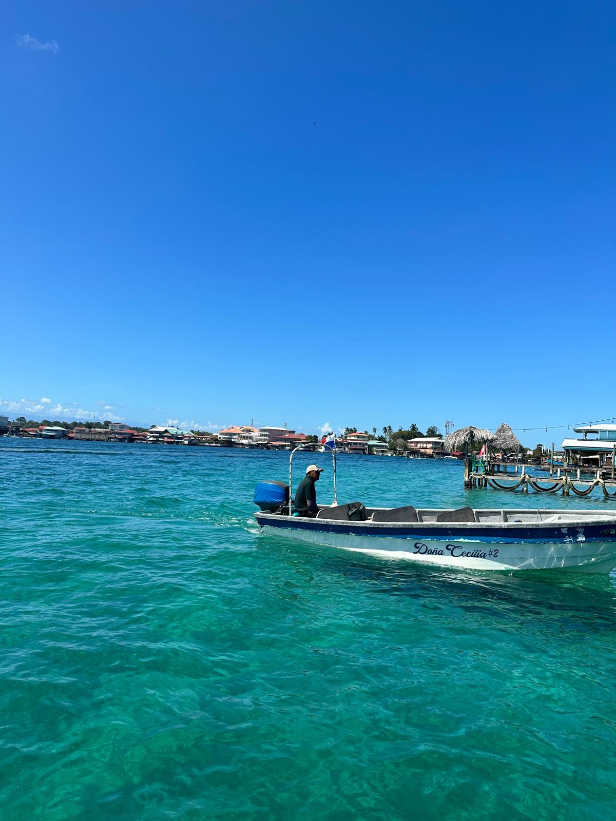 Panga boat on crystal clear turquoise water with Bocas Town waterfront in the background